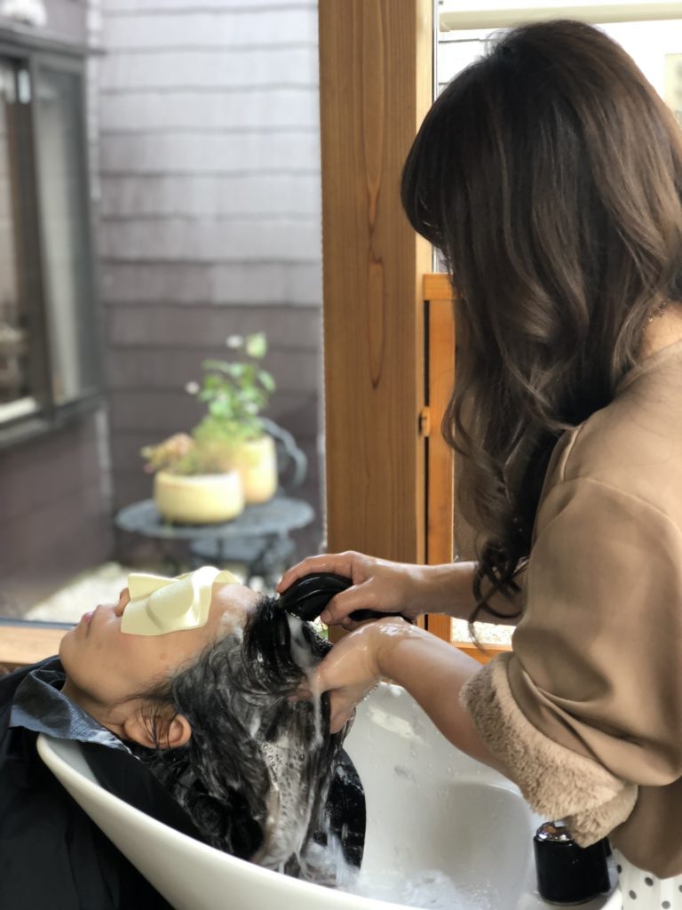 オシャレなヘアサロンでシャンプーを受けている女子とスタイリストさん