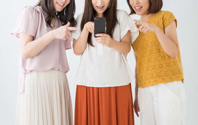 スマホを見て会話する女性の写真