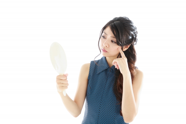 鏡ののぞいて髪型を気にする女性
