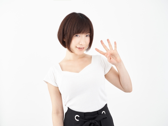 4本指を立てている白いシャツを着た若い女性