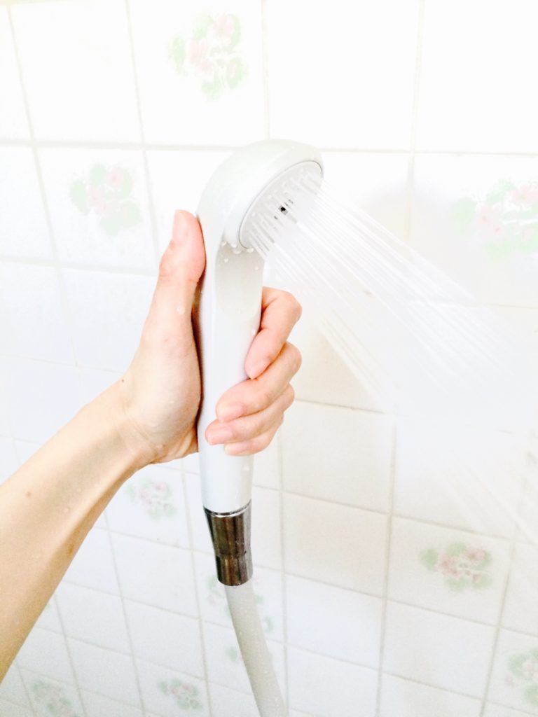 熱いお湯のシャワーを持つ女性の手