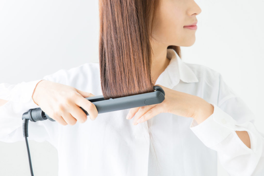 ヘアアイロンを使う女性の写真