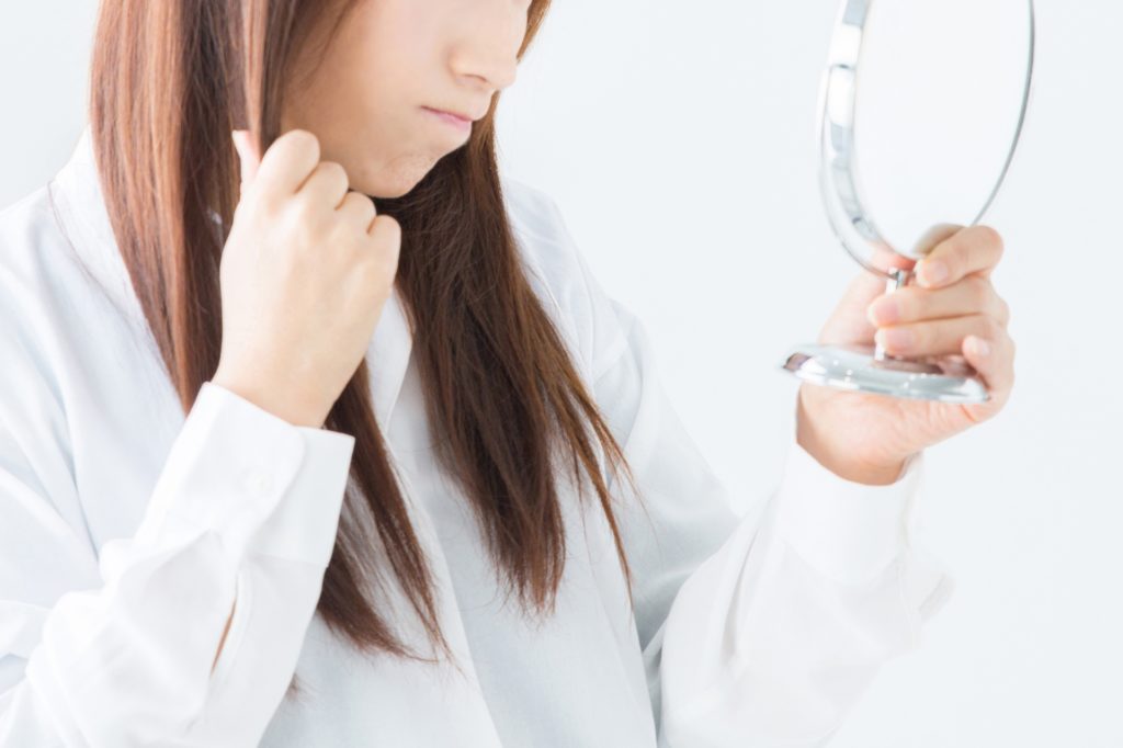 鏡を見る髪の長い女性の写真