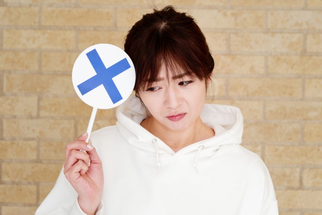 バツのプラカードを持つ女性の写真