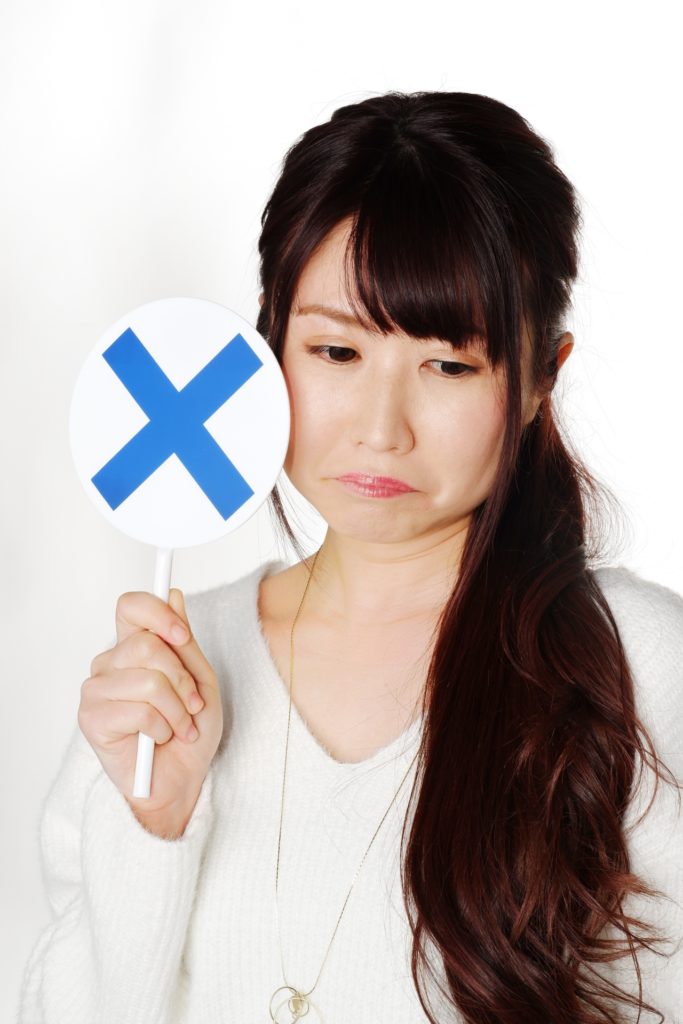 バツのプラカードを持つ女性の写真