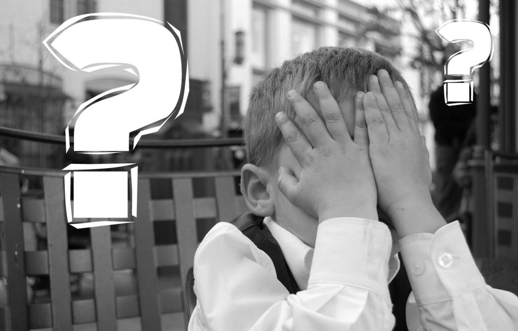 顔を手で押さえて悩んでいる少年の写真