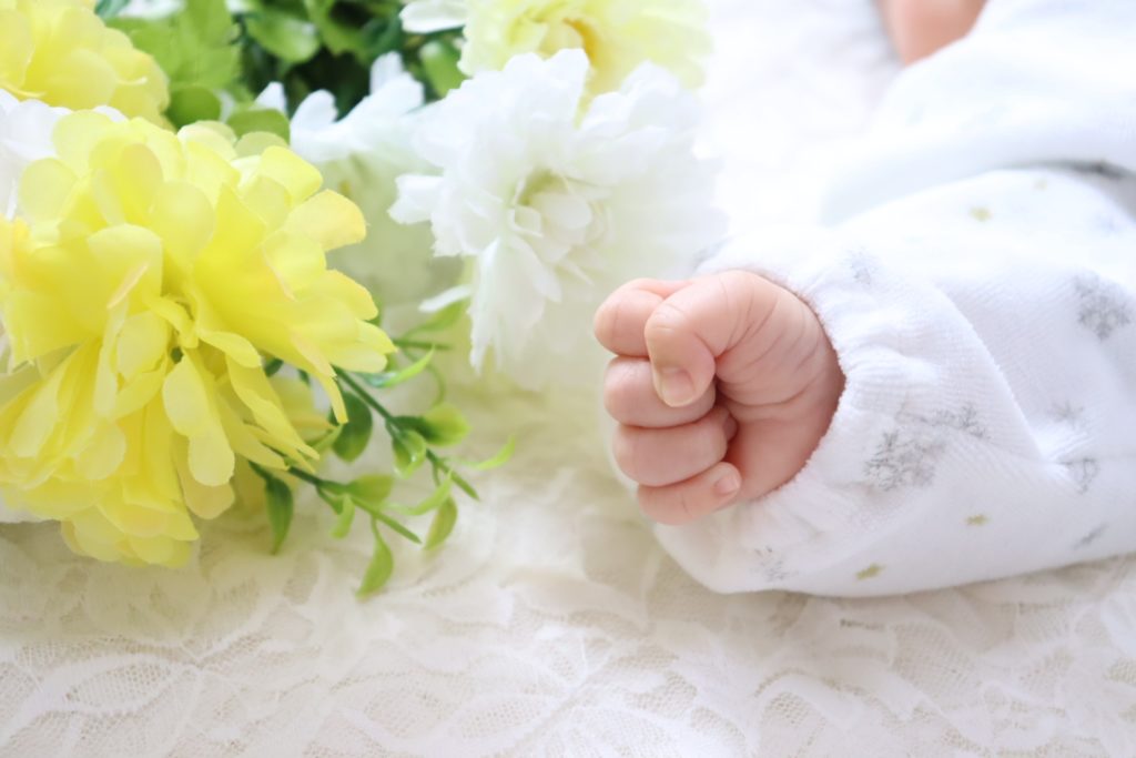 赤ちゃんの手と黄色の花の写真
