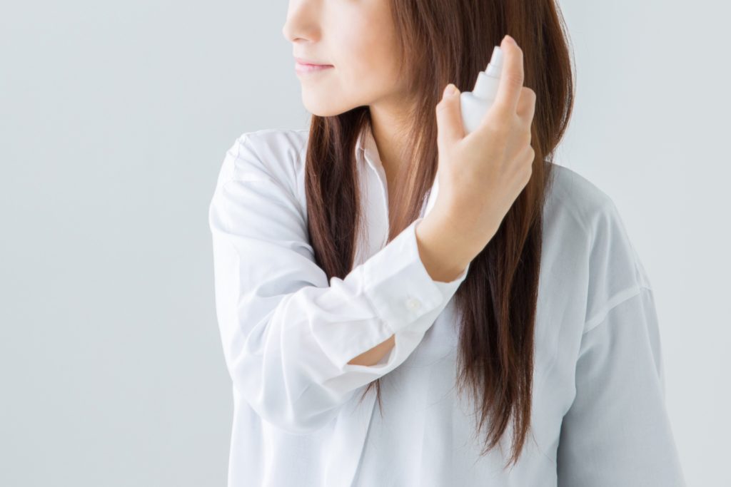 頭にスプレーをしている女性の写真