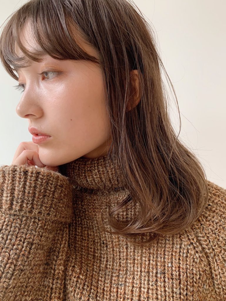 あごに手を添えるミディアムヘアの女性の写真