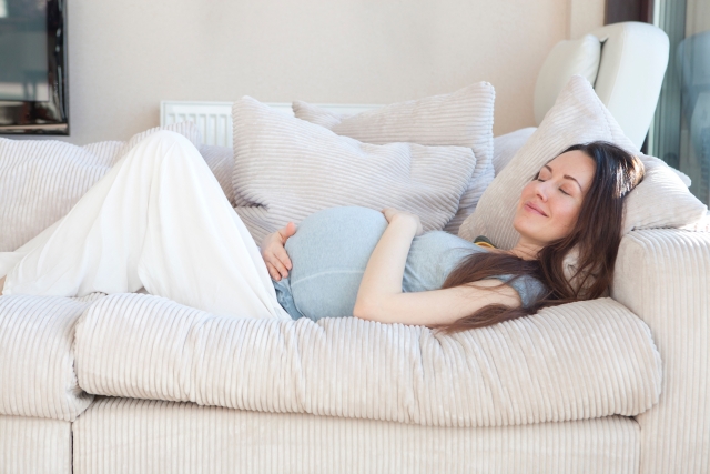 ソファに寝そべる妊婦