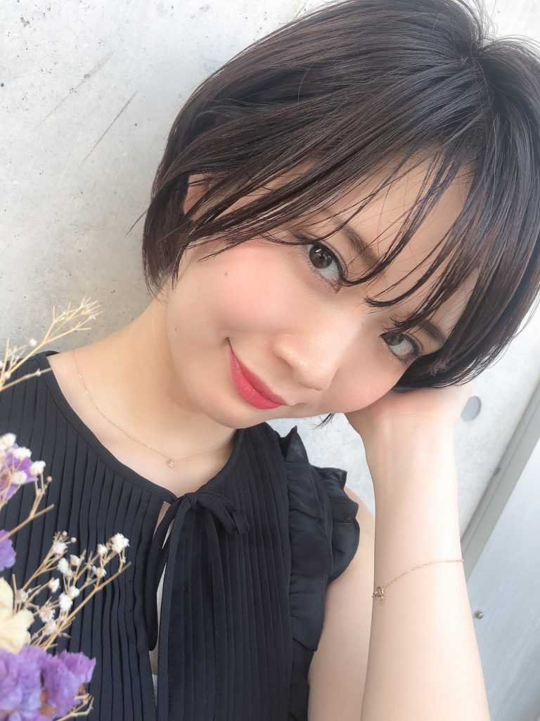 耳元に手を当てている、軽めな前髪の女性の写真