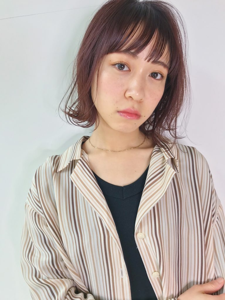 パツっとした前髪がよく似合うストライプのシャツを着た女性の写真