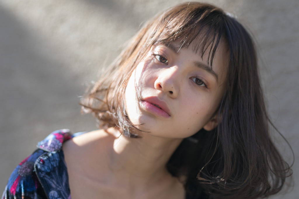 斜めに顔を傾けるボブヘアの女性の写真