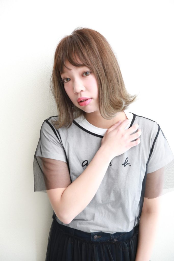 鎖骨を触る外ハネボブヘアの女性の写真