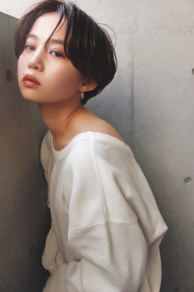やや長めの目にかかる前髪が、知的なイメージを引き立てるショートヘアの女性の写真