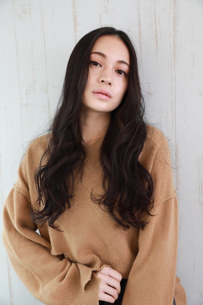 センター分け前髪で、全体的にボリュームアップして見えるロングヘアの女性の写真