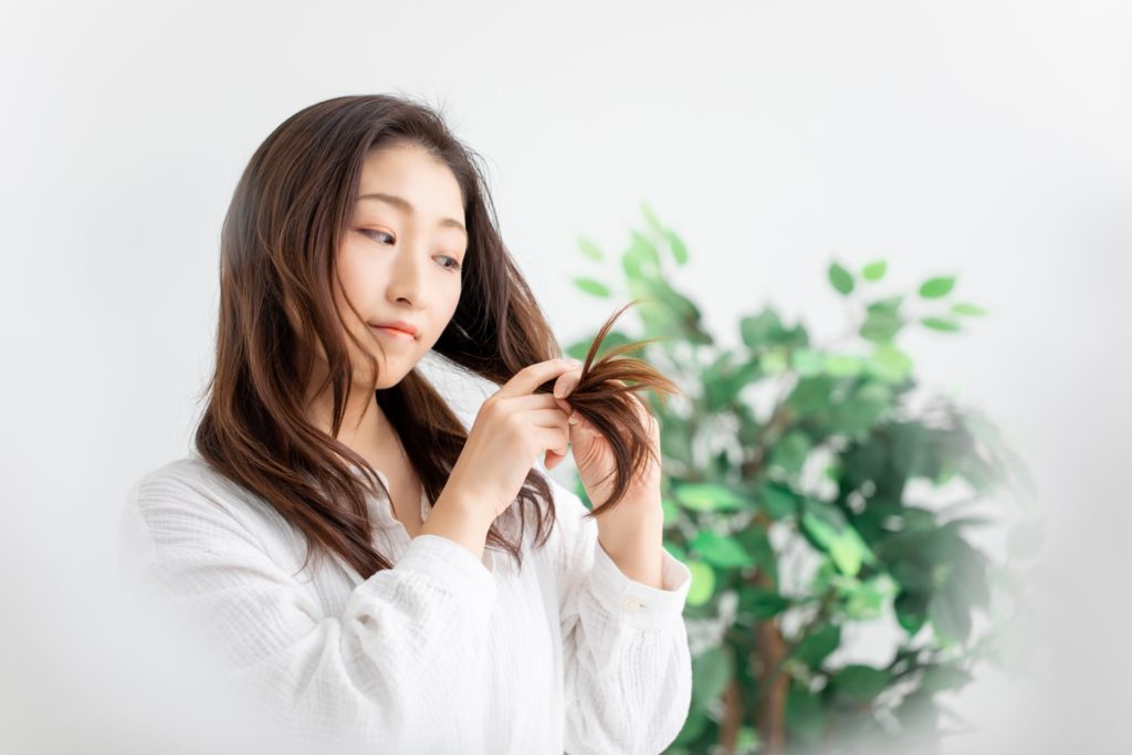 毛先を触りながらチェックしている女性の写真