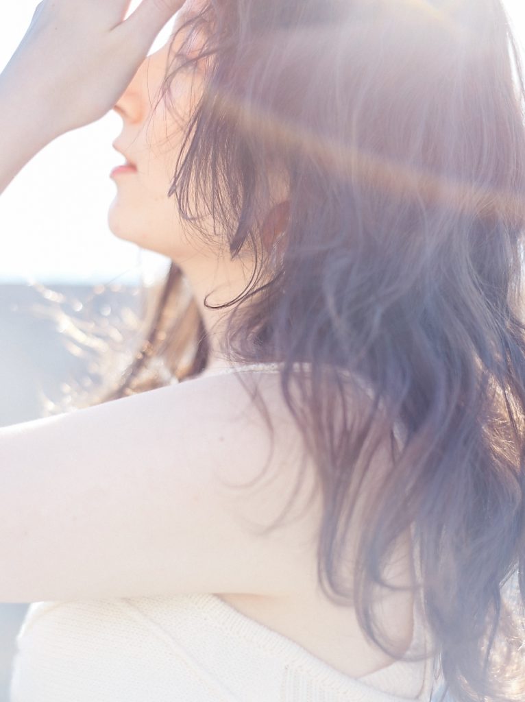 陽の光に照らされたふんわりとやわらかいウェーブヘアの女性の写真