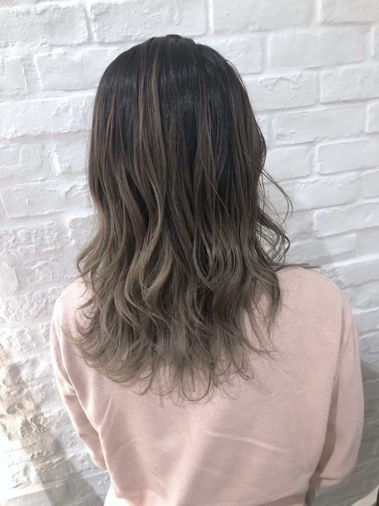 落ち着いたグレージュのバレイヤージュカラーをしたロングヘアの女性の写真