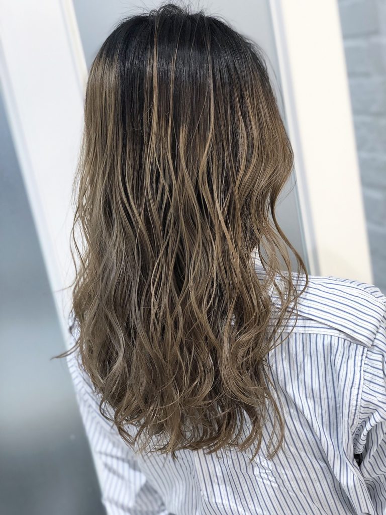 明るめベージュアッシュのバレイヤージュカラーをしたロングヘアの女性の写真