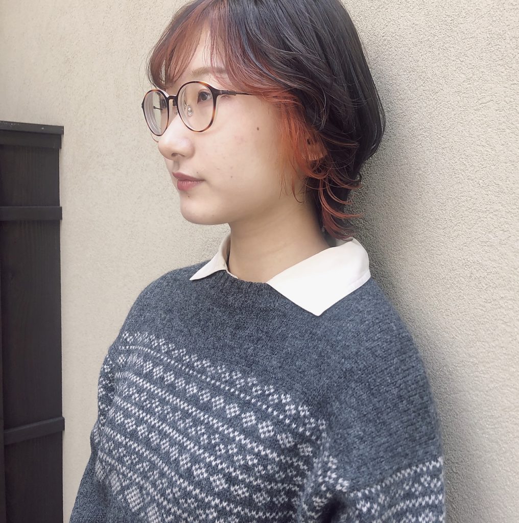 ななめ前髪と顔周りをオレンジのフェイスフレーミングカラーに染めた女性の写真