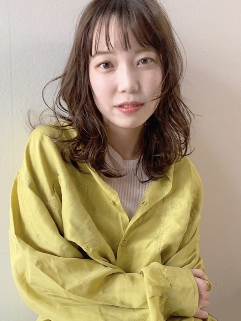ミックスカールと短め前髪がかわいいミディアムヘアの女性の写真