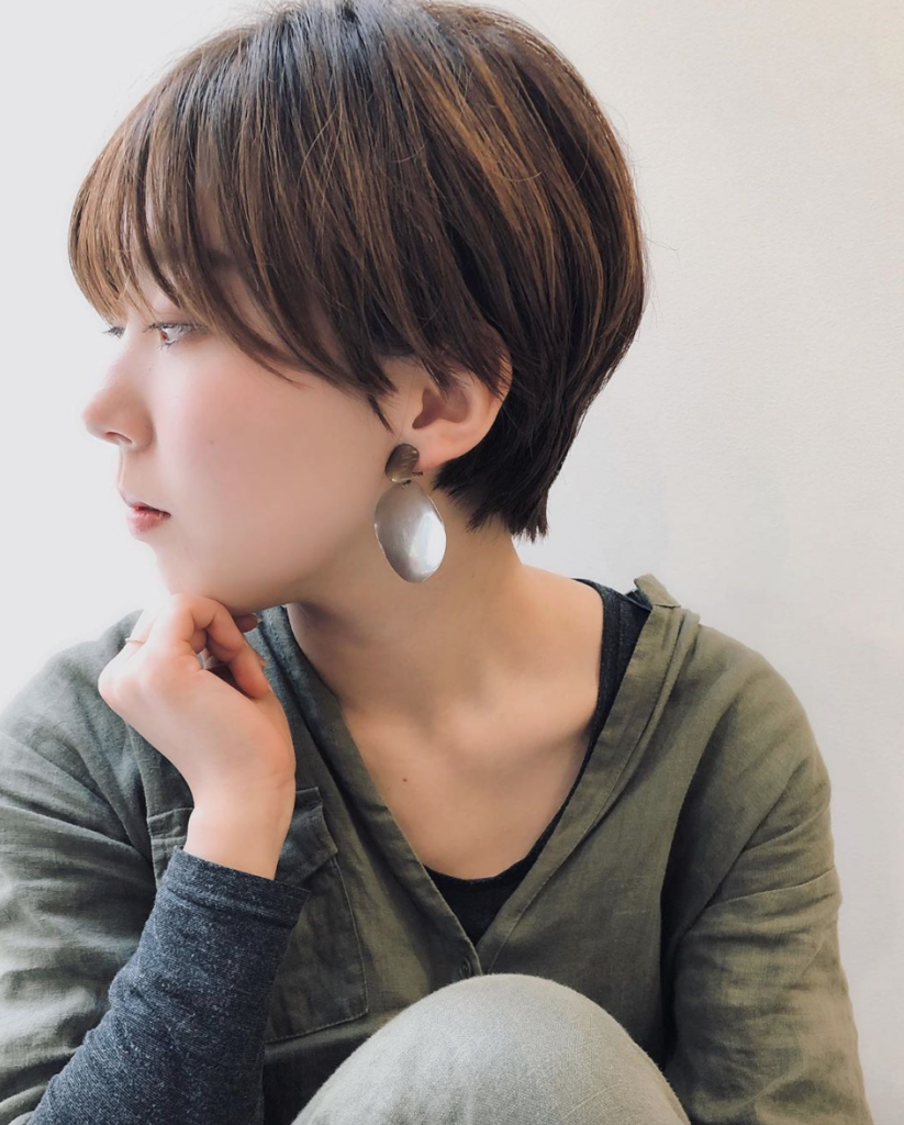 ショートヘアの女性が横向きで頬杖をついている様子