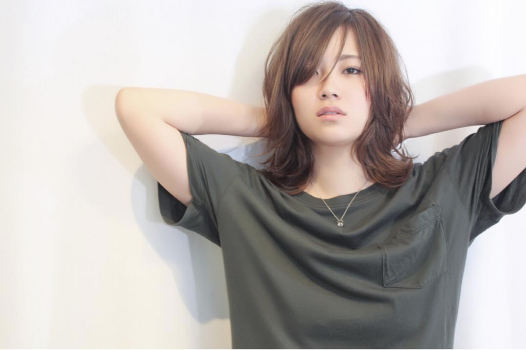 頭の後ろに手を置いて正面を見る女性の写真