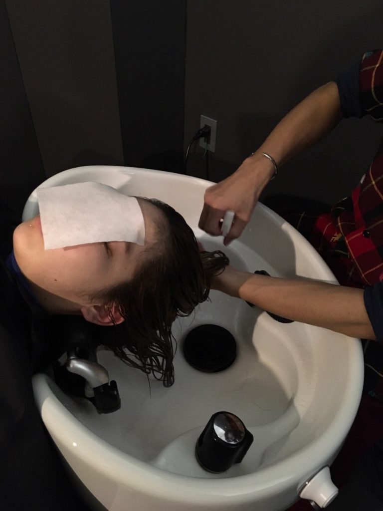 髪に導入剤をスプレーしている写真