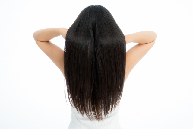 黒髪ストレートヘアを持ち上げようとする女性