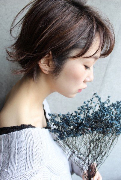 花を持って横を向いたショートヘアの女性の写真