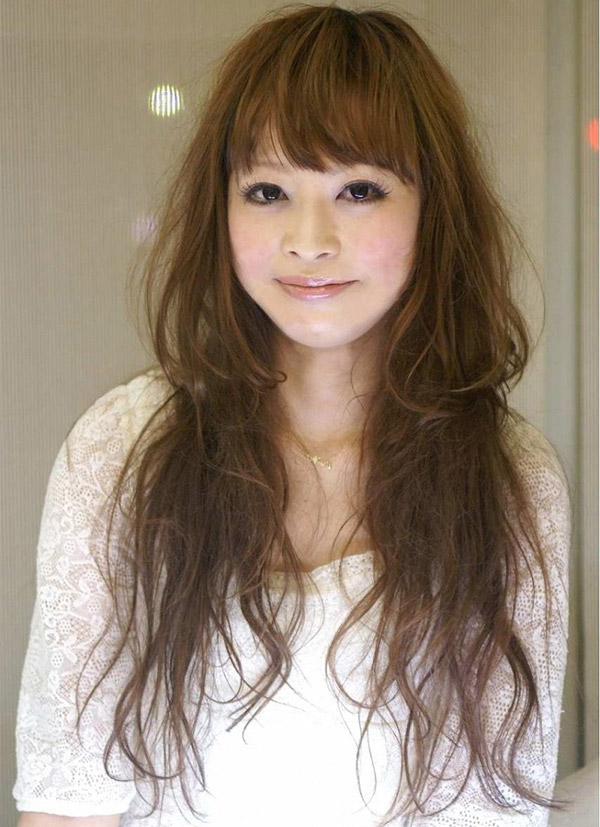 ナチュラルなパーマをかけたロングヘアーの女性が笑っている写真