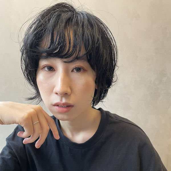 ショートスタイルの女性が手を顔に当てた写真