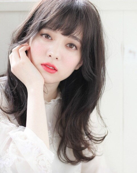 ほほに手を当てて首をかしげた女性の写真