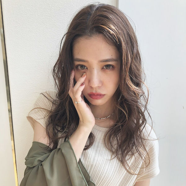 顔に手を当ててうつむき加減の女性の写真