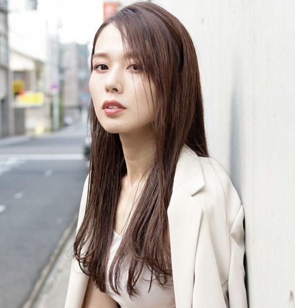 壁にもたれたロングヘアの女性の写真