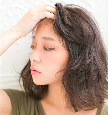 髪をかき上るしぐさの女性の写真
