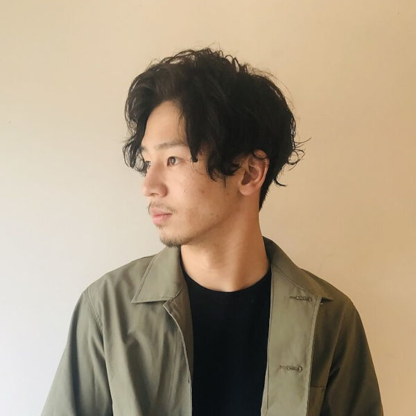 パーマスタイルの男性が横を向いている写真