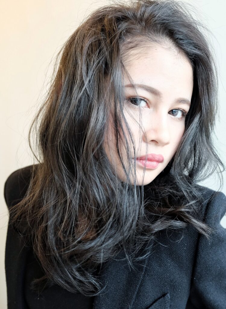 透け感のあるグレージュカラーのロングスタイルの女性の写真